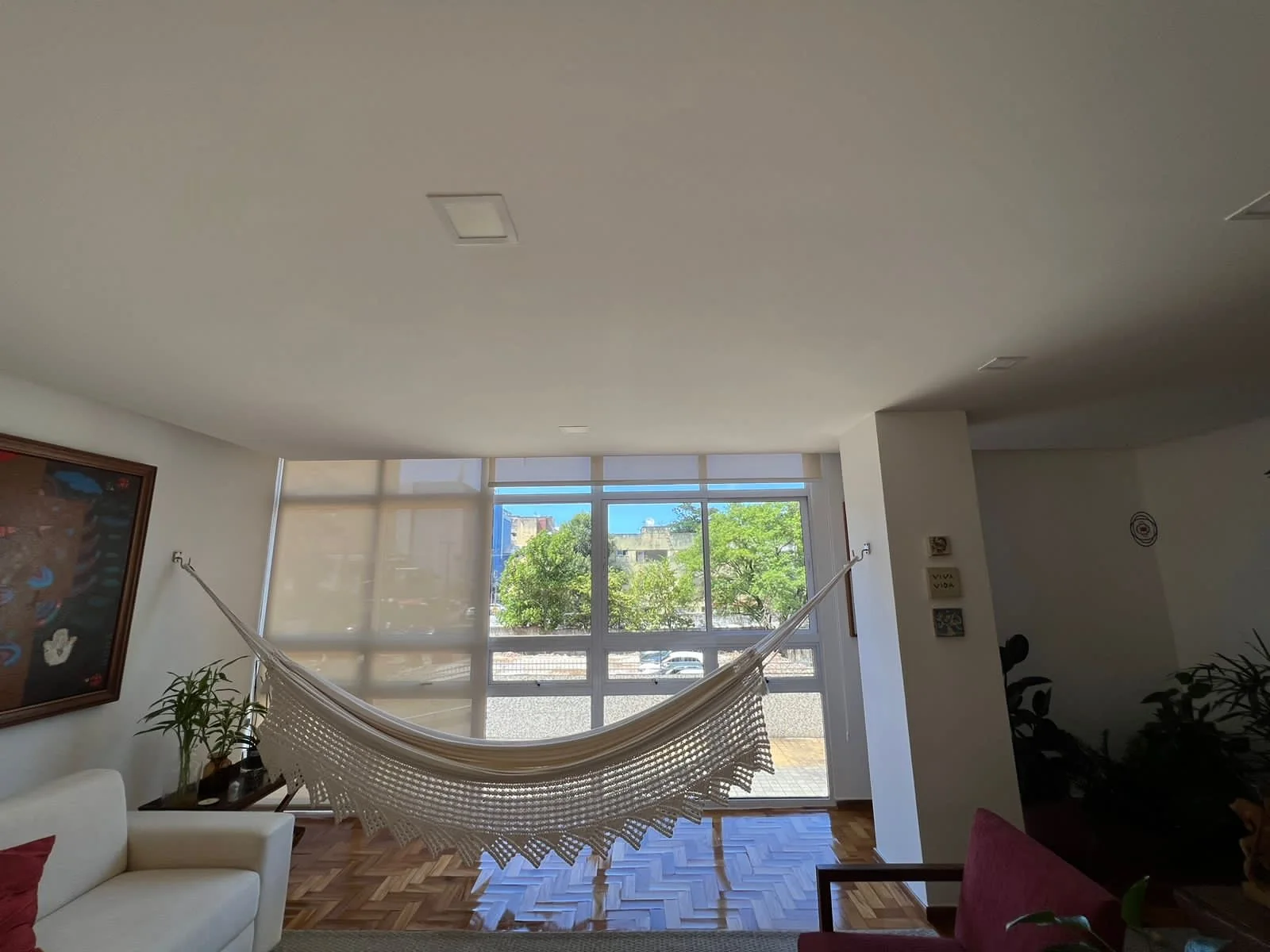 Sala residencial clara com rede e grandes janelas